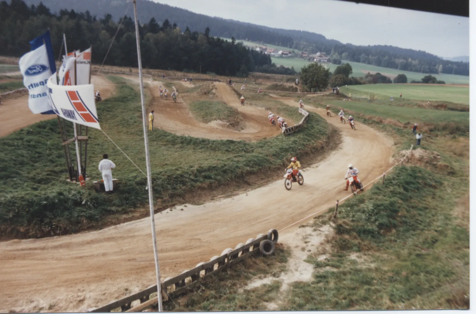 Blick über die Strecke am Thannhof mit Fahnen im Vordergrund, Aufnahme aus den 1980er-Jahren